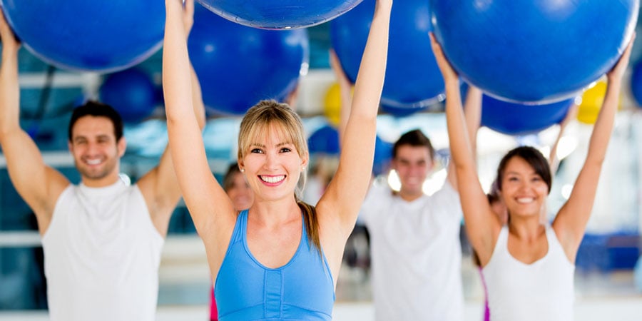Group of people in a Pilates class holding a fitness ball
