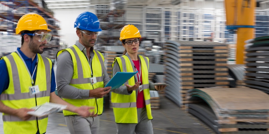 FACTORY EMPLOYEES WITH HARD HATS WALKING AND TALKING