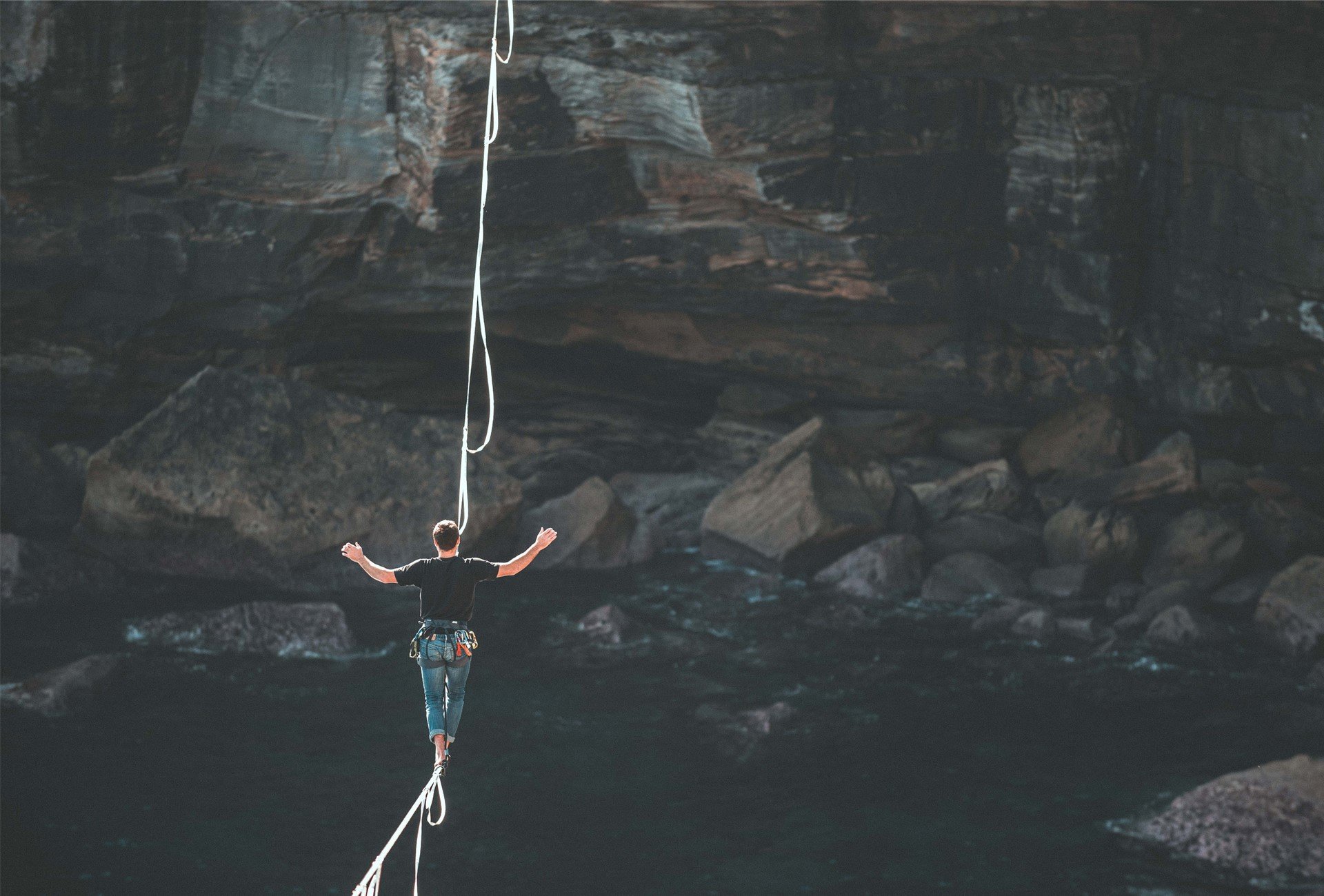 Man on tightrope over cliff edge and running water flip