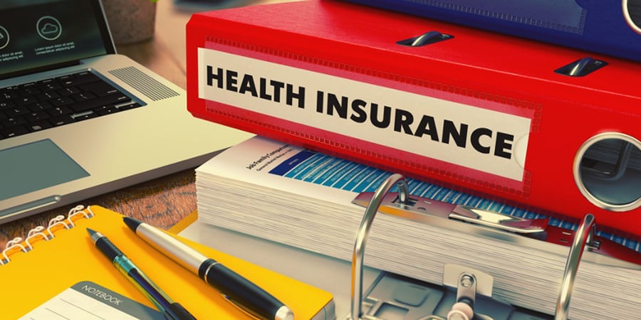 Red Office Folder with Inscription Health Insurance on Office Desktop with Office Supplies and Modern Laptop. Business Concept on Blurred Background. Toned Image.-1