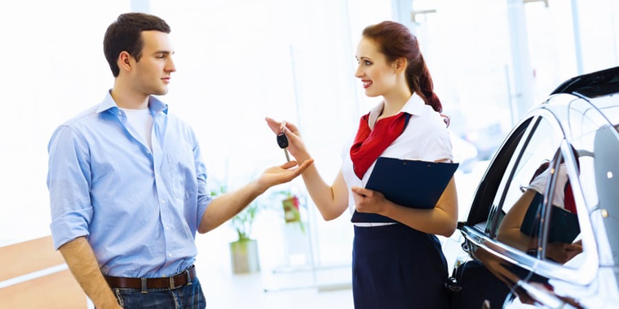 Young man choosing car at salon with help of consultant