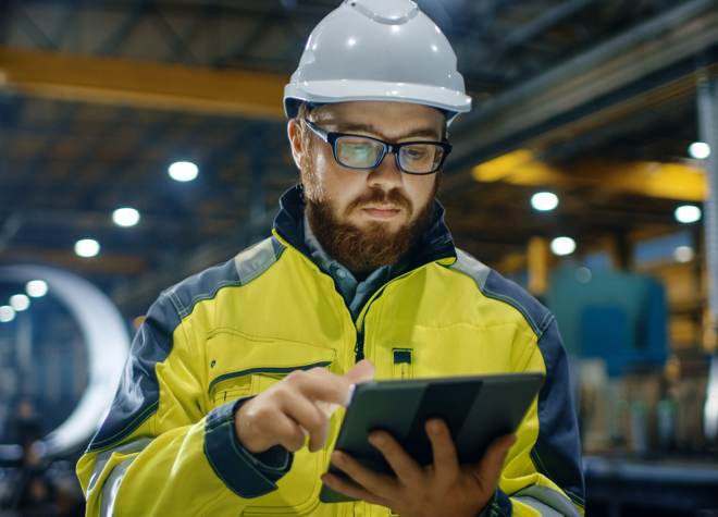 person-wearing-hard-hat-working-on-tablet-in-manufacturing-environment